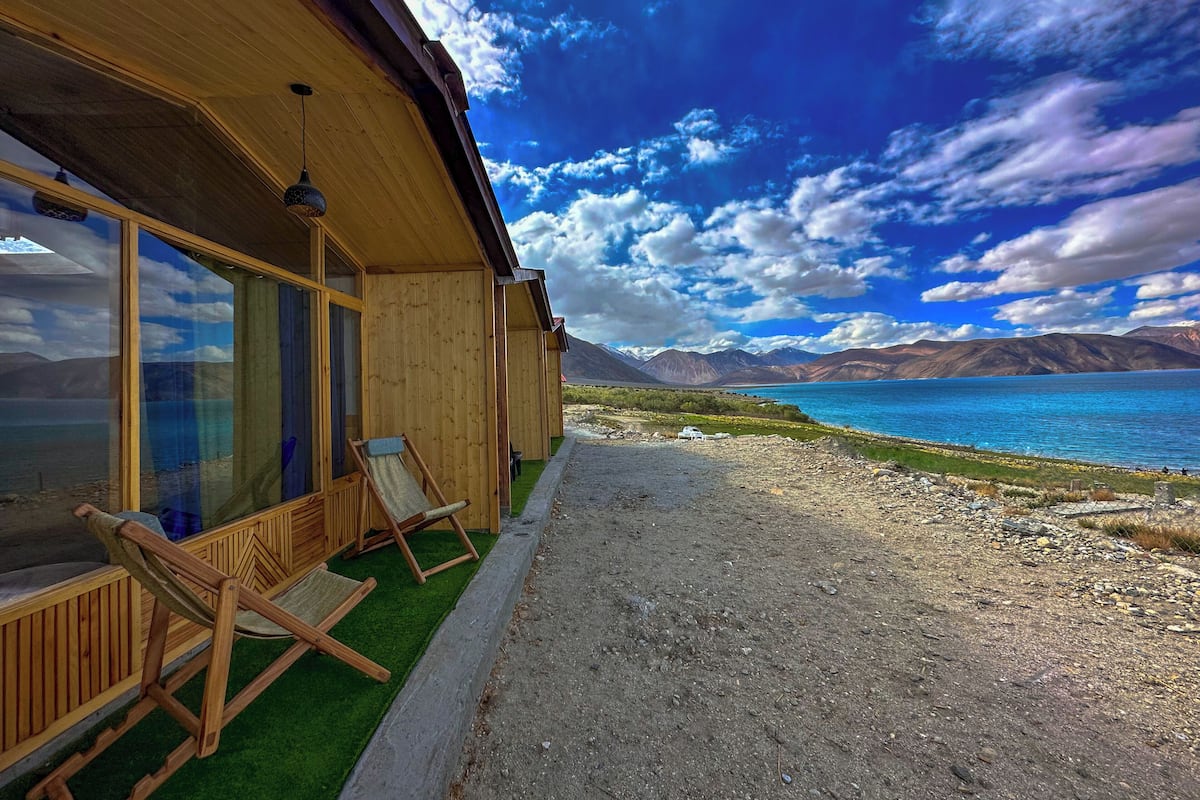 Una cabaña de madera con vistas a un lago y montañas.