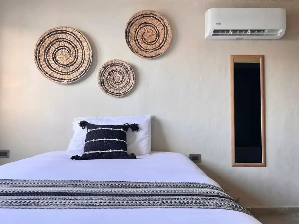 A bedroom with a bed, a wall-mounted air conditioner, and three circular wall decorations.