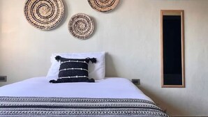 Ein Schlafzimmer mit einem Bett, einer Wandklimaanlage und drei runden Wandbildern.