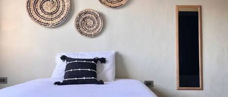 A bedroom with a bed, a wall-mounted air conditioner, and three circular wall decorations.
