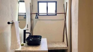 Une salle de bain équipée d’un lavabo, d’un miroir, d’un porte-serviettes et d’une fenêtre.