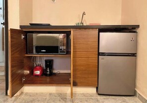 A compact kitchenette with a microwave, a coffee maker, and a refrigerator.