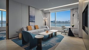 Un salon moderne avec un canapé, une table basse et une vue sur le paysage urbain, grâce à de grandes fenêtres.