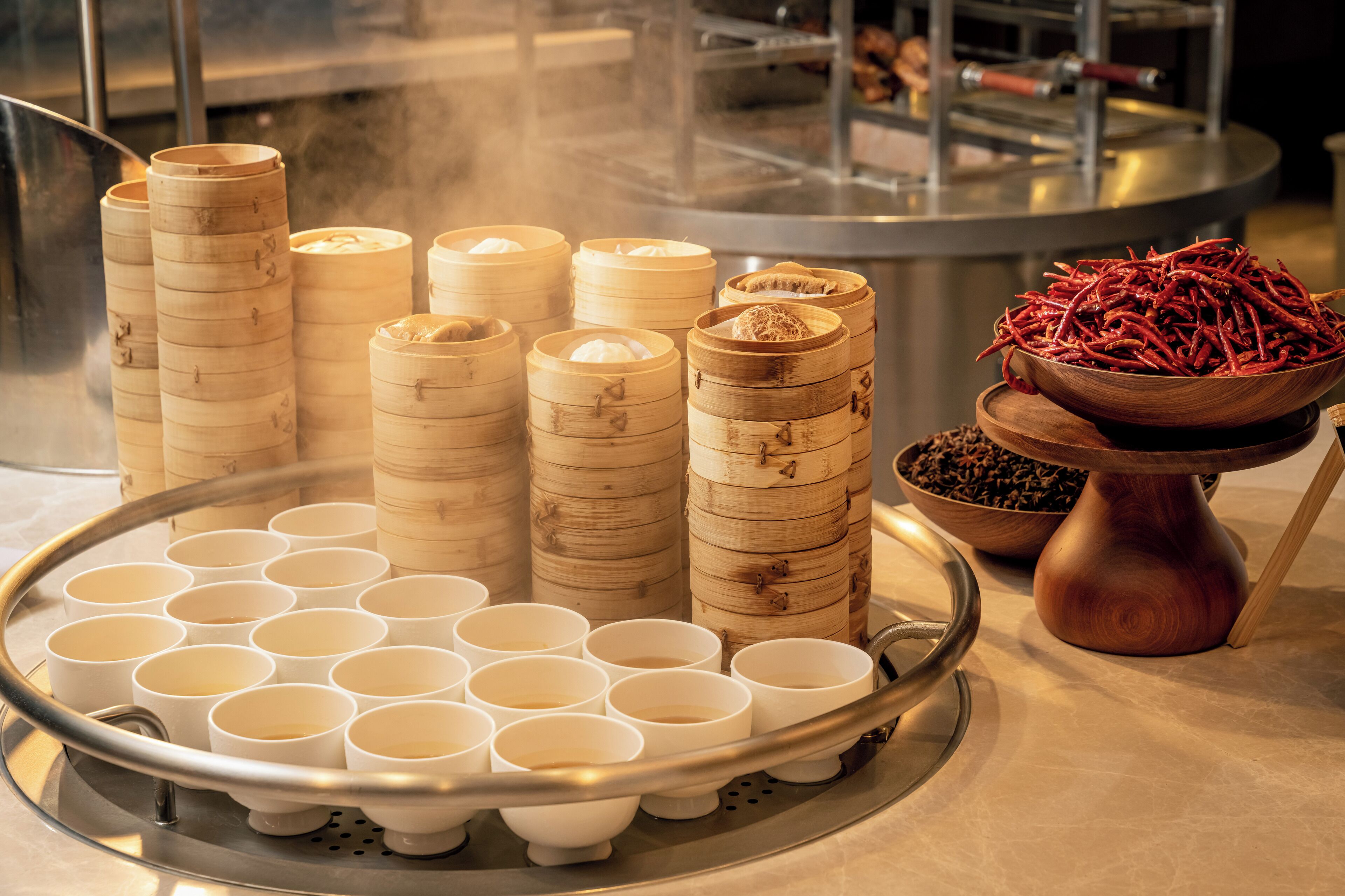 A steamer with bamboo containers and a tray of white cups, likely for tea or food service.