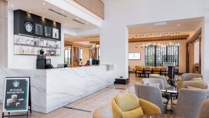A modern hotel lobby with a marble reception desk, seating area, and a large screen displaying the hotel name. - Holiday Inn Sepang Airport by IHG (Sepang)