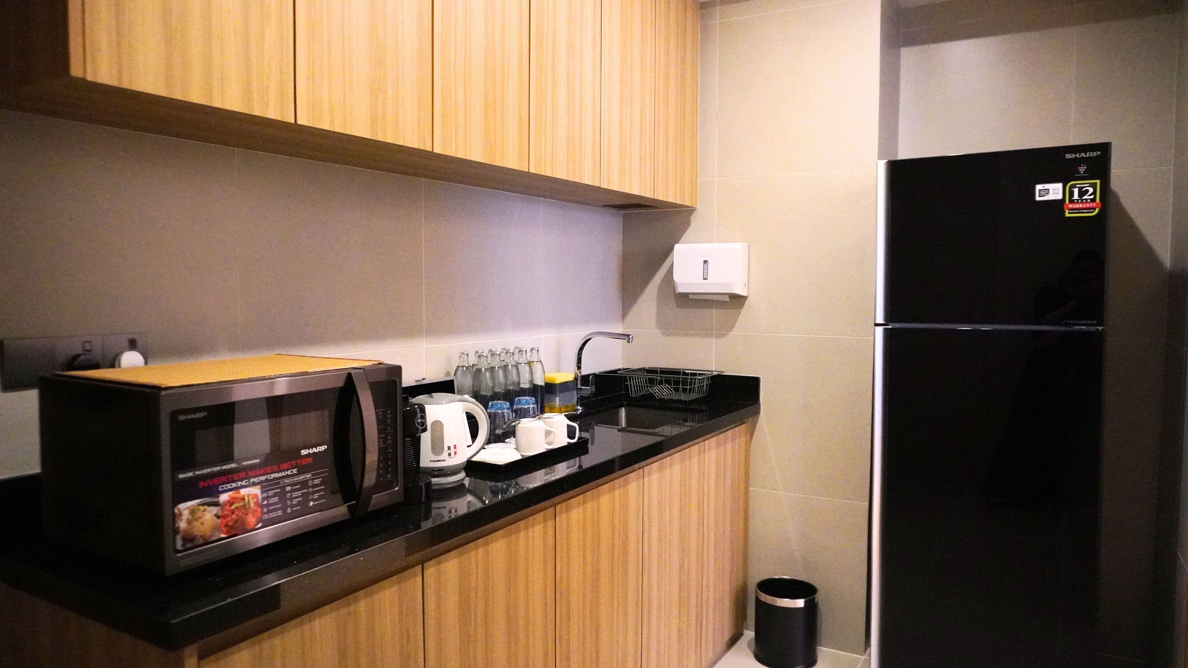 Una cocina con microondas, cafetera y un refrigerador negro.