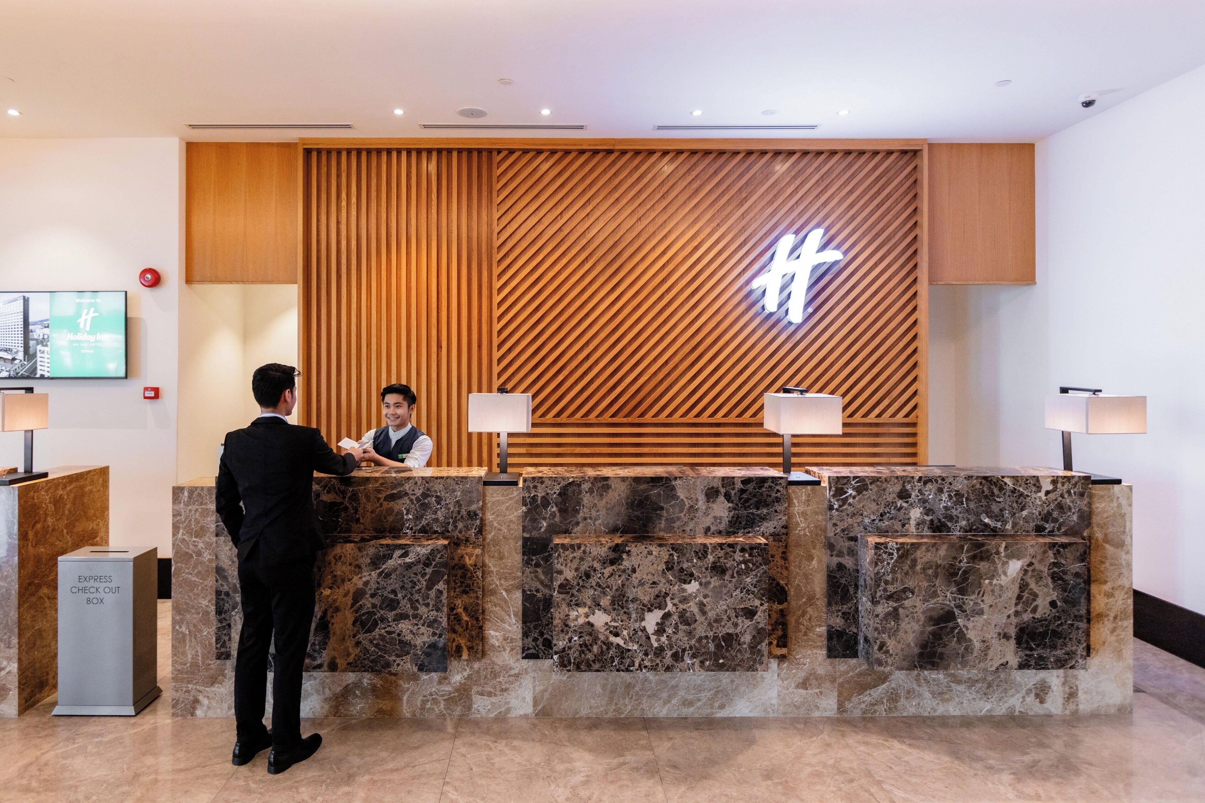 Una recepción de hotel con diseño de panel de madera y un gran letrero iluminado.
