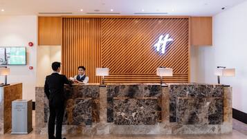 Una recepción de hotel con diseño de panel de madera y un gran letrero iluminado.