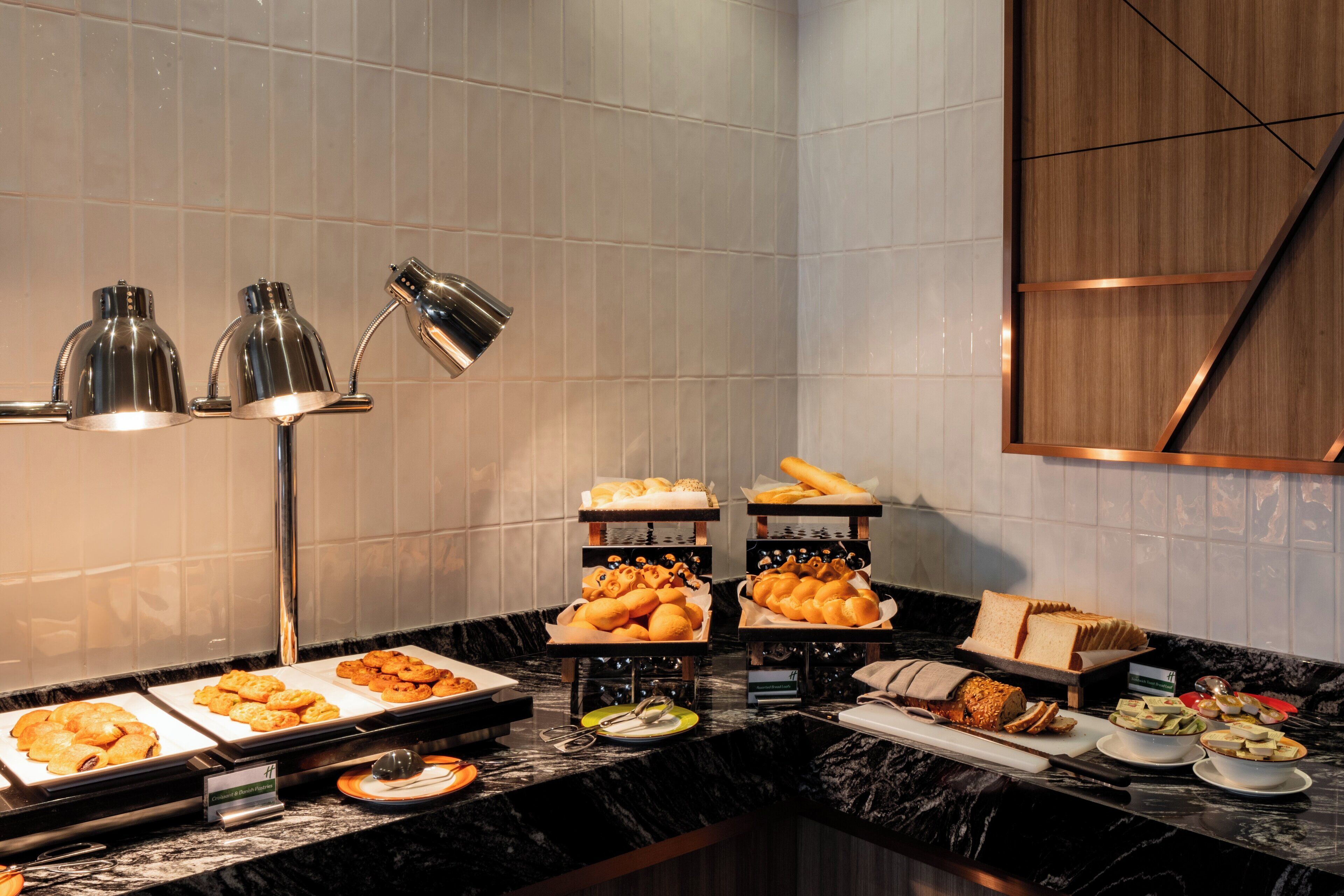 A buffet with various food items, including pastries and bread, arranged on a marble countertop.