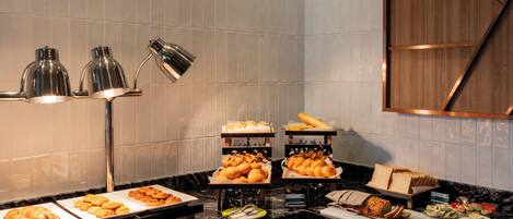 A buffet with various food items, including pastries and bread, arranged on a marble countertop.