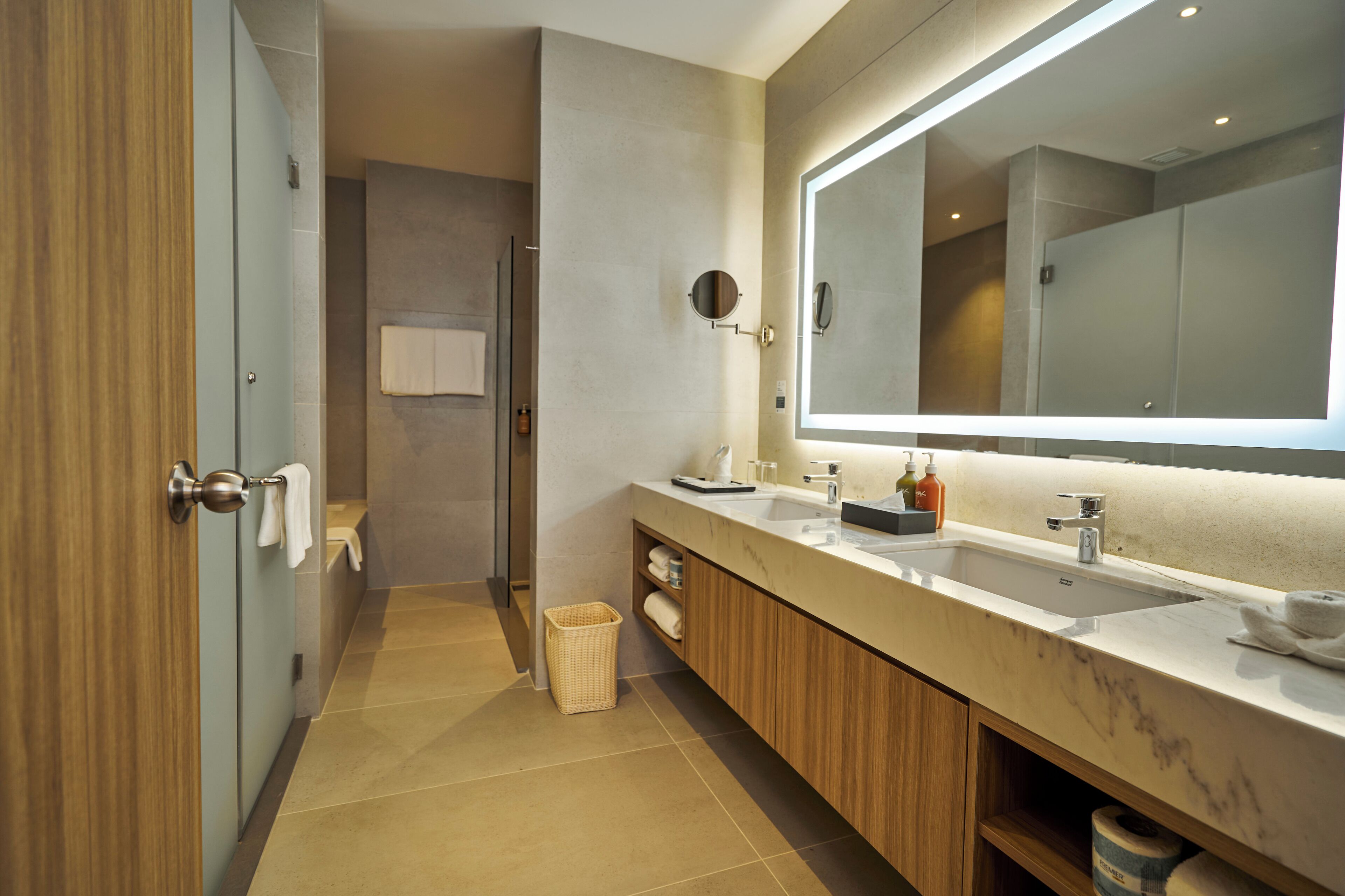 A modern bathroom with two sinks, a large mirror, and a shower area.