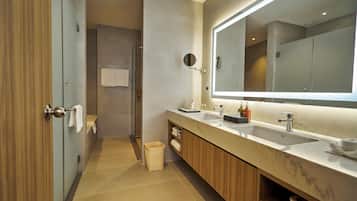 A modern bathroom with two sinks, a large mirror, and a shower area.