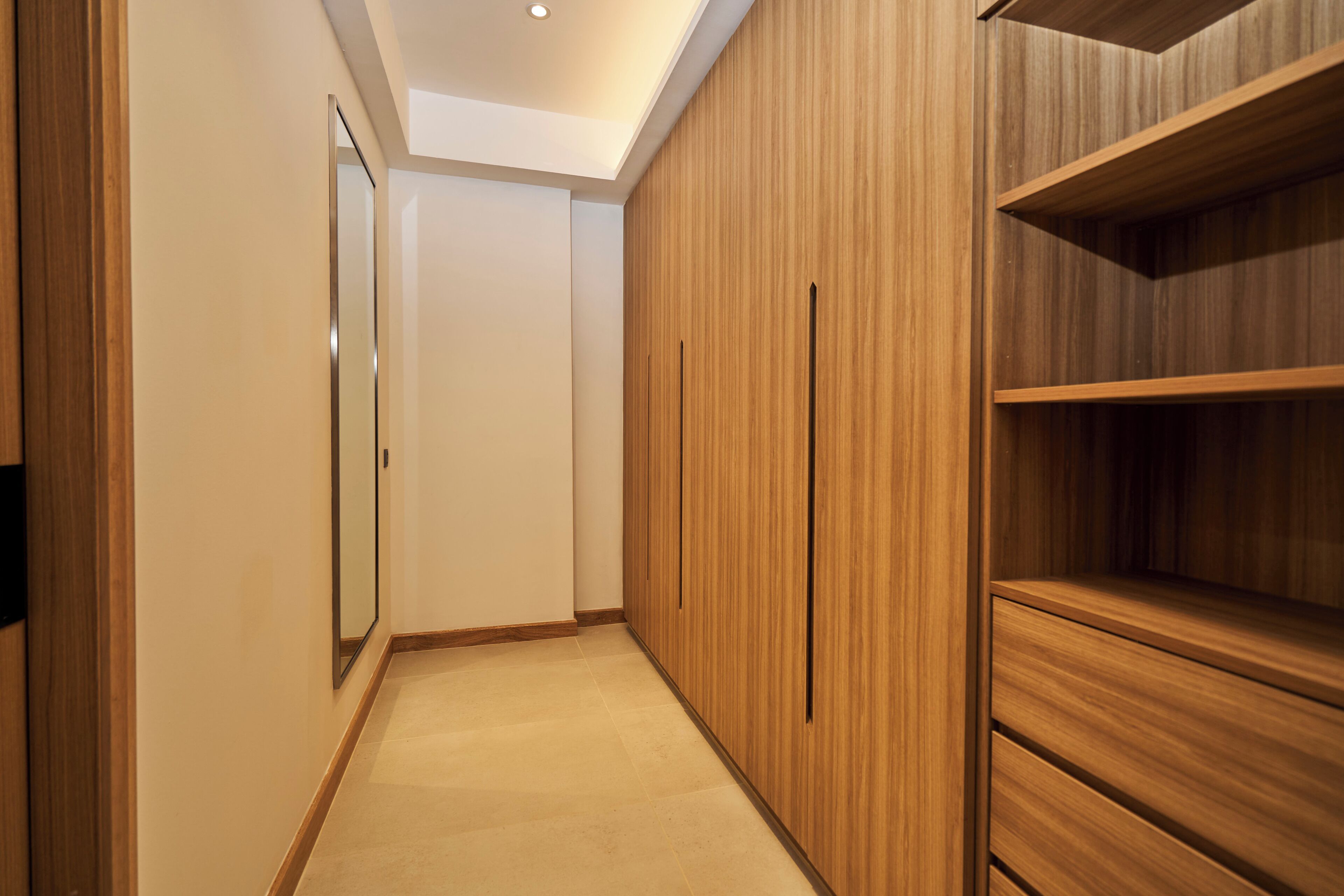A hallway with wooden paneling and a mirror on the left.
