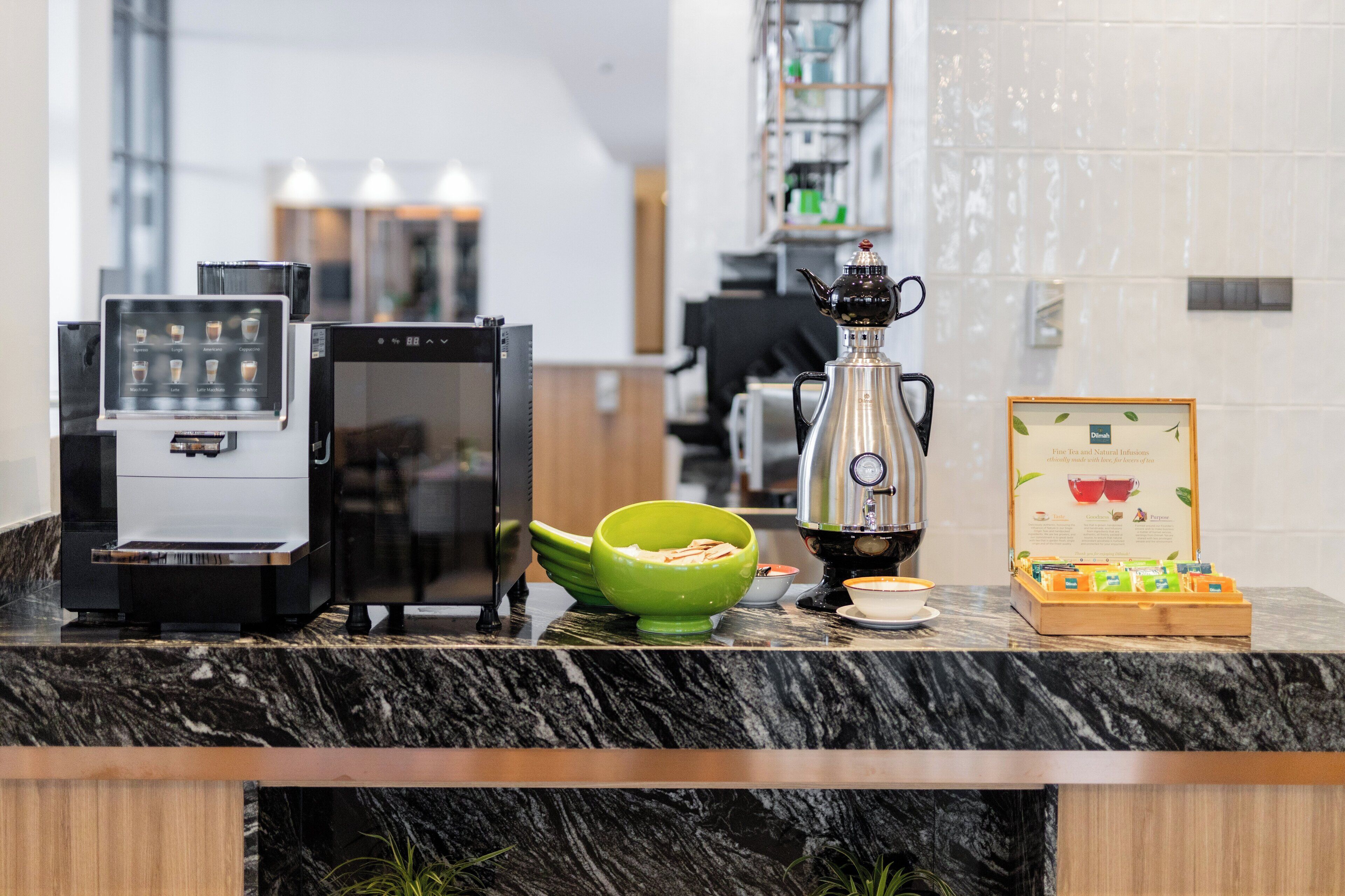 A coffee station with a coffee machine, a teapot, a green bowl, and a menu stand.