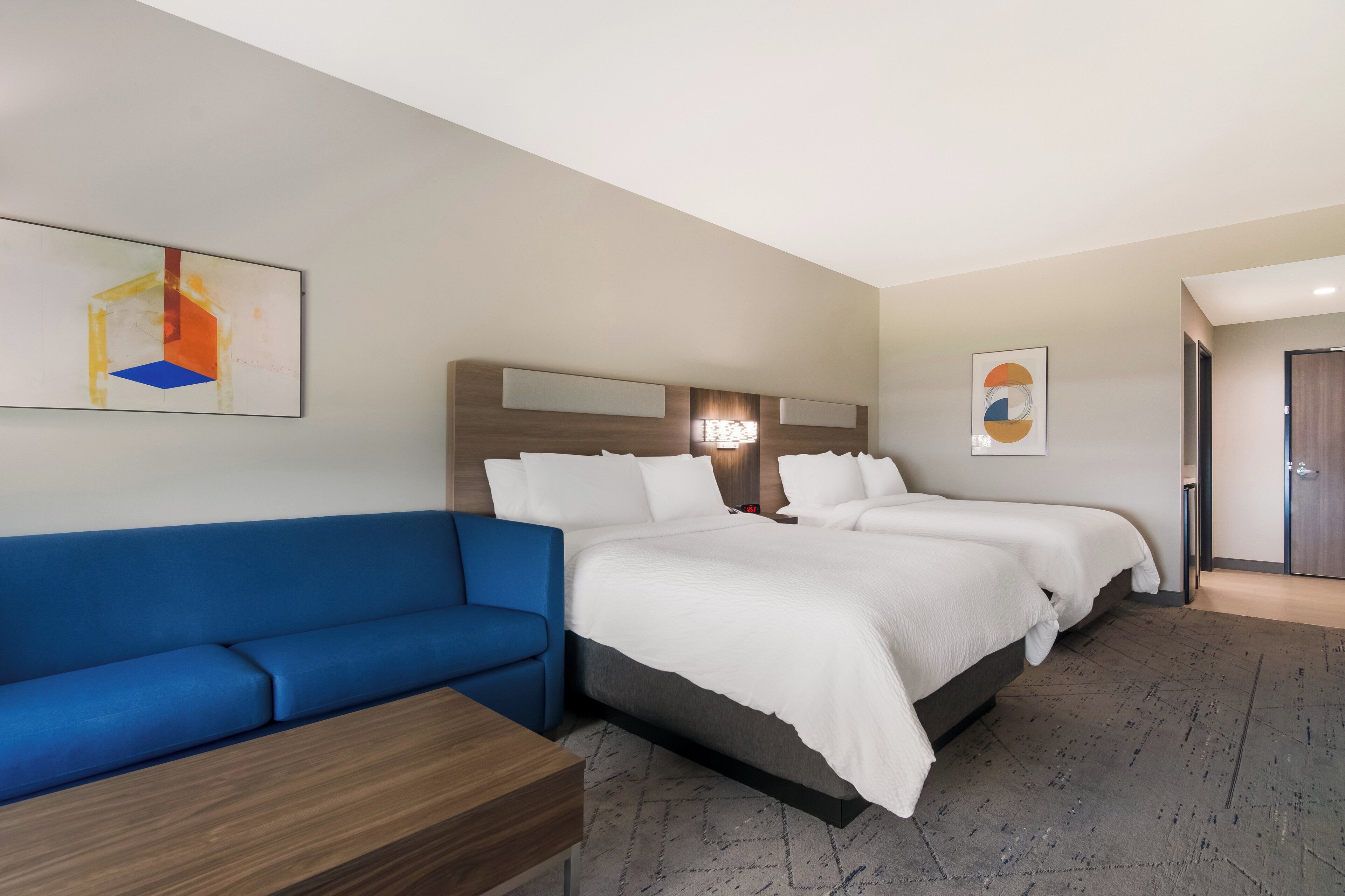 A hotel room with a bed, a blue sofa, and a wooden side table.