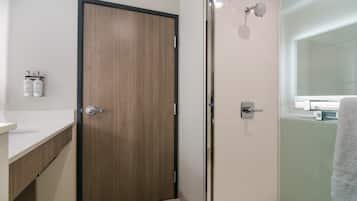Un bagno moderno con una porta in legno, cabina doccia in vetro e lavandino bianco.