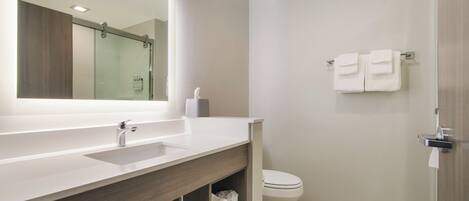A modern bathroom with a large mirror, a sink, a toilet, and a shower area.