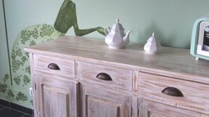 A light-colored wooden dresser with three white teapots and a green wall with a floral pattern. - La Rosa - Romantic lake view apartment (Trevignano Romano)