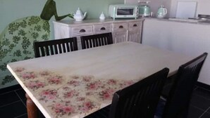 A dining area with a table covered by a floral tablecloth, surrounded by chairs. - La Rosa - Romantic lake view apartment (Trevignano Romano)