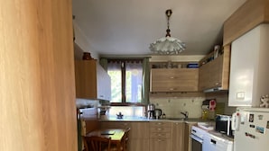 Una cocina con armarios de madera, una mesa de comedor con sillas, un refrigerador y una estufa.