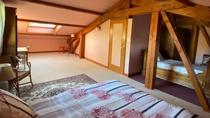 Un dormitorio con una cama, una silla, una mesita y una ventana.