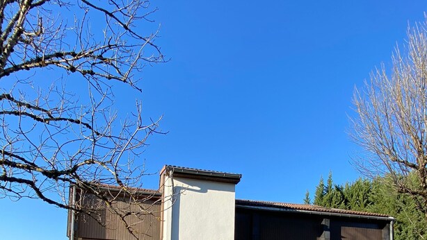 Un edificio moderno de dos pisos con un amplio acceso de vidrio y un patio cubierto.