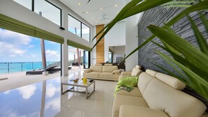 A spacious living room with a large sofa, a coffee table, and a view of the ocean. - Chaweng Peak Villas - 8 Bedrooms Villa With Infinity Pools (Ko Samui)