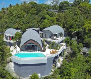 A modern villa with a pool, surrounded by lush greenery.