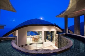 A modern building with a curved roof and a glass-walled dining area.