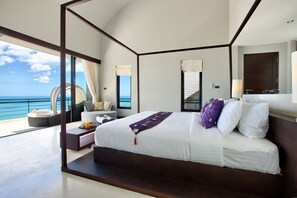 A modern bedroom with a large bed, a view of the ocean, and a balcony.