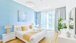 A modern hotel room with a large bed, bedside tables, a desk, and a view of the city through large windows. - Al Bateen - Ultra Luxury JBR - Private Beach and Pool (Dubai)