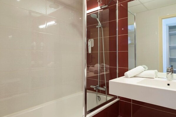 A bathroom with a glass-enclosed shower, a white sink, and a mirror.