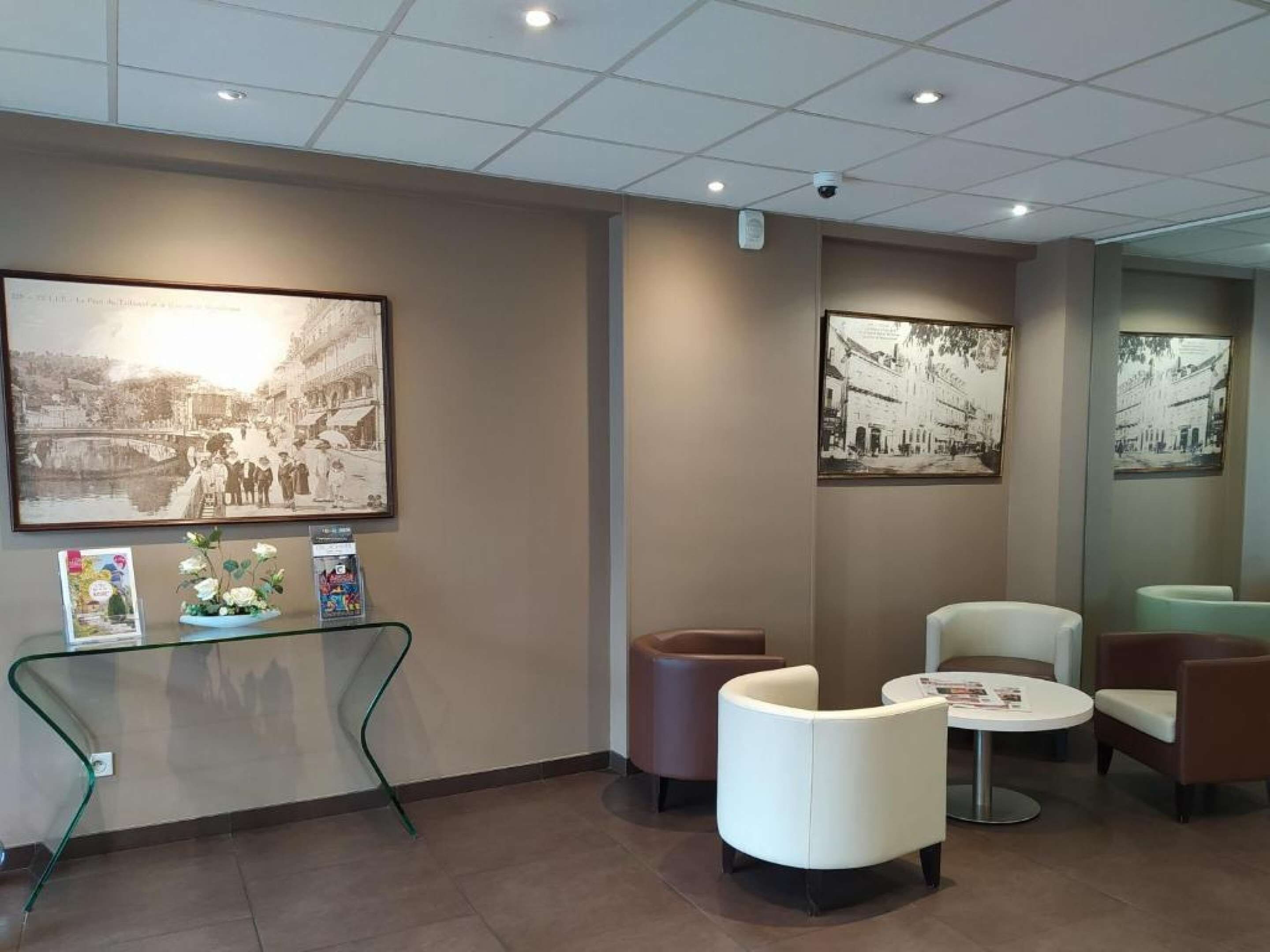 Een receptie met een glazen tafel, zwart-wit foto’s in lijsten aan de muur en modern meubilair.