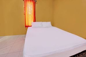 Quarto com cama, janela com cortinas laranja e paredes amarelas.