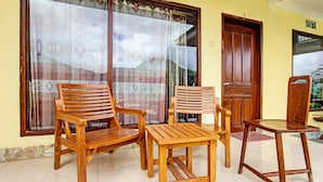 Une pièce meublée de meubles en bois, comprenant deux chaises et une table, de grandes fenêtres avec des rideaux et une porte en bois.