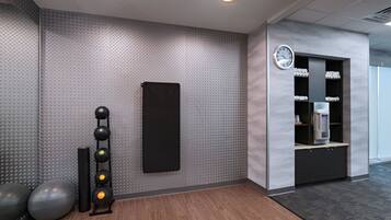 A gym with exercise balls, a wall-mounted weight rack, and a water dispenser.