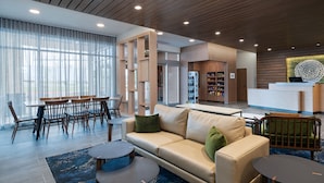 A modern hotel lobby with a wooden ceiling, a reception desk, a seating area with a sofa and chairs, and a bookshelf. - Fairfield Inn & Suites By Marriott Austin Georgetown (Georgetown)