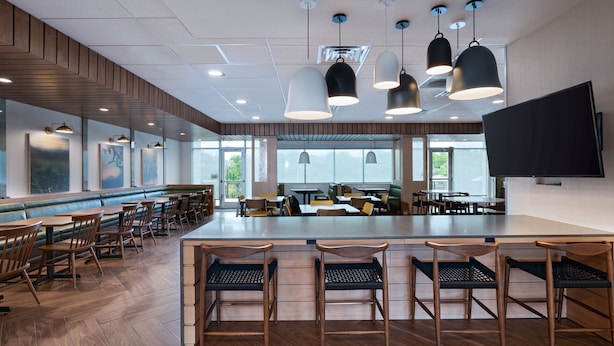 A spacious restaurant with wooden flooring, multiple tables and chairs, pendant lighting, and large windows offering natural light. - Fairfield Inn & Suites By Marriott Austin Georgetown (Georgetown)