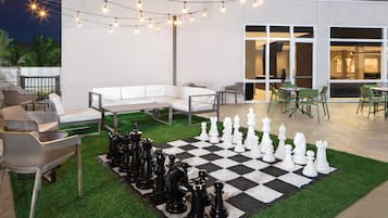 Un patio al aire libre con un tablero de ajedrez, luces colgantes y asientos.