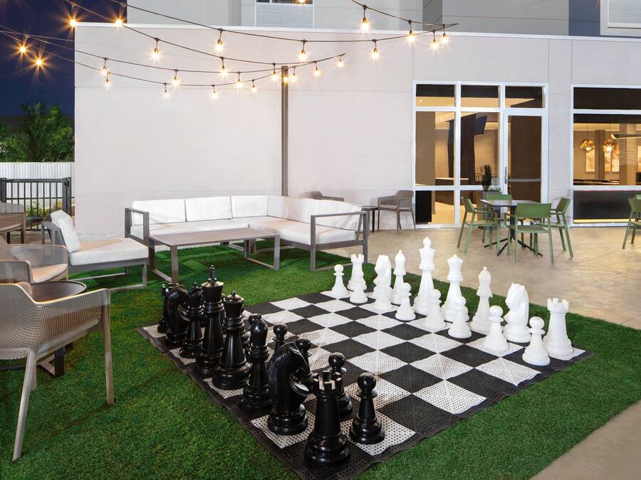 Un patio al aire libre con un tablero de ajedrez, luces colgantes y asientos.