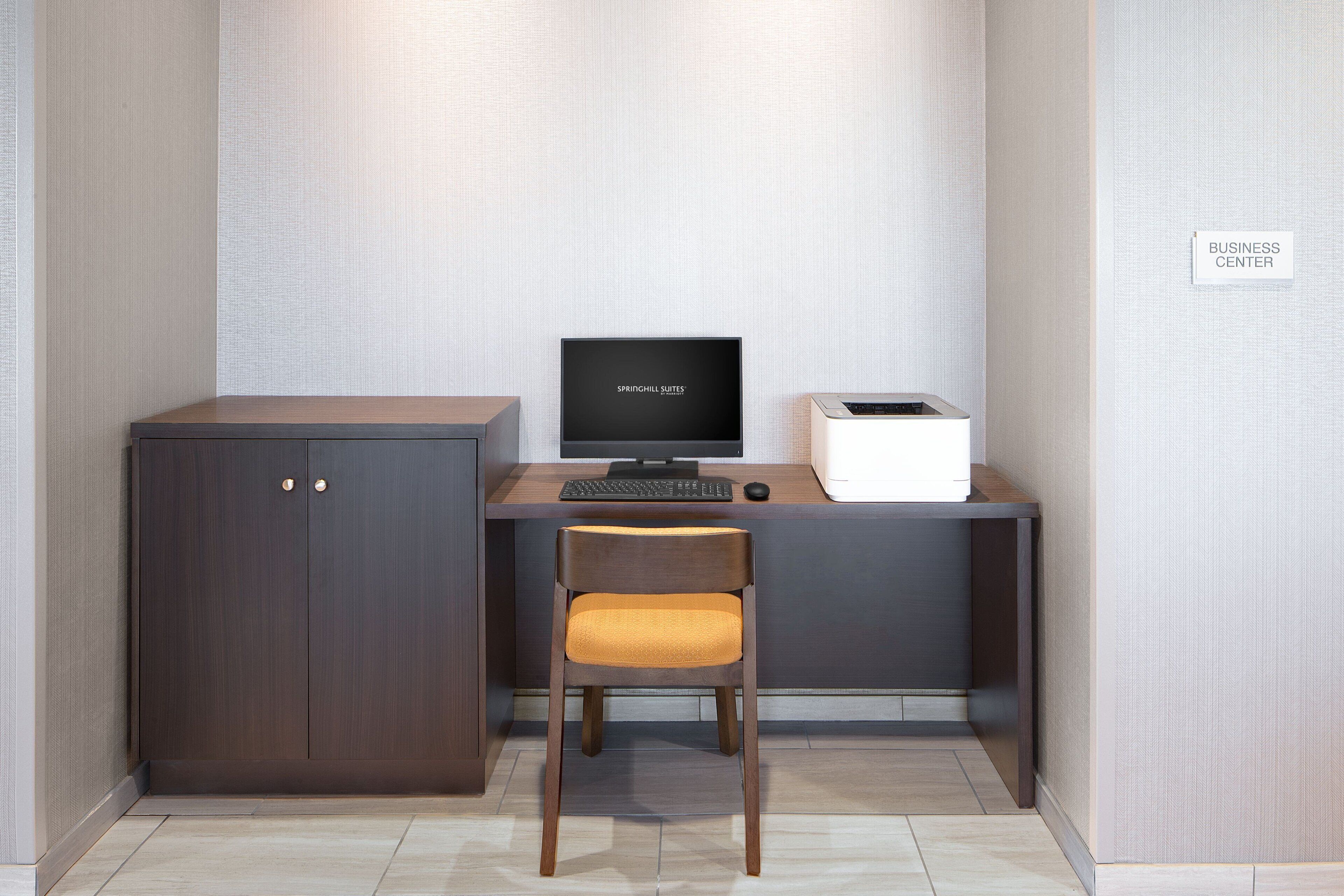 A compact workspace with a desk, computer, and storage unit, labeled as a business center.