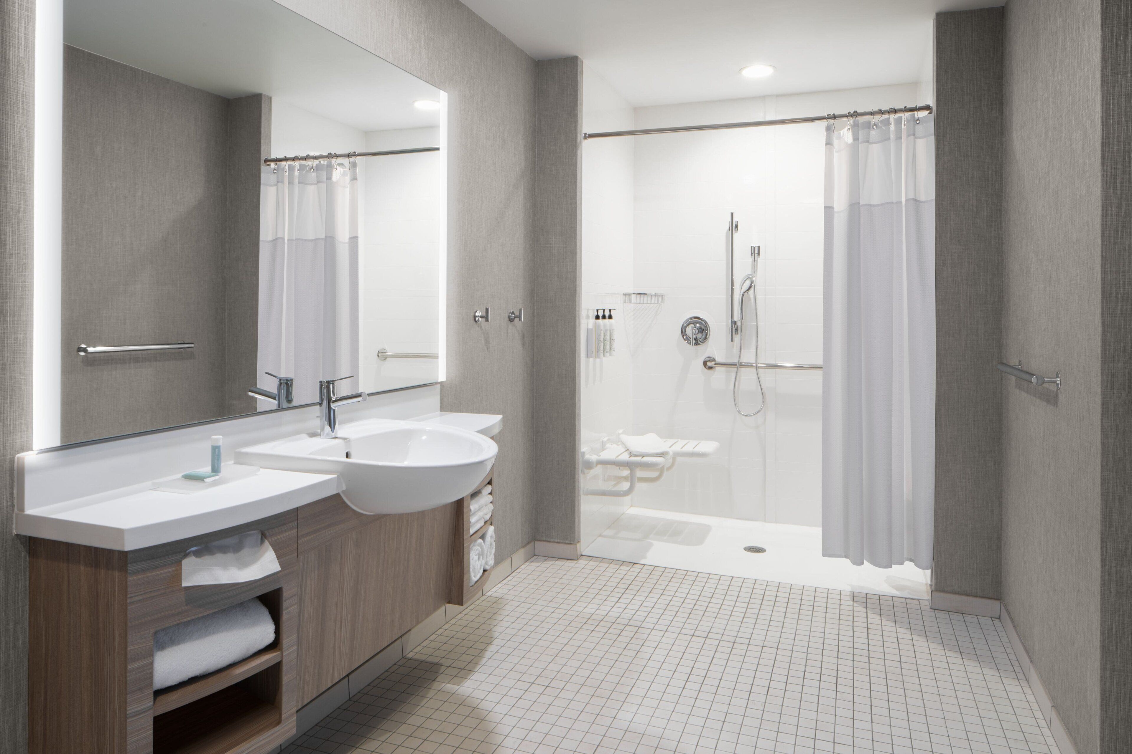 A modern bathroom with two sinks, a large mirror, and a walk-in shower.