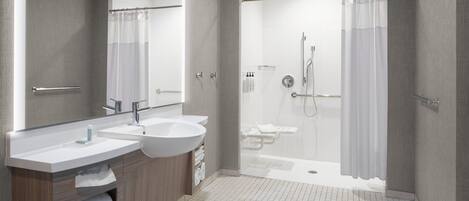 A modern bathroom with two sinks, a large mirror, and a walk-in shower.