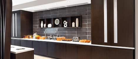 A modern kitchen with dark wood cabinets, a white countertop, and various kitchen appliances.