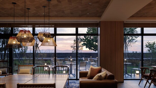 A modern interior with a large dining table, comfortable seating, and large windows offering a view of the outdoors. - Fairfield by Marriott Kagoshima Sakurajima (Tarumizu)