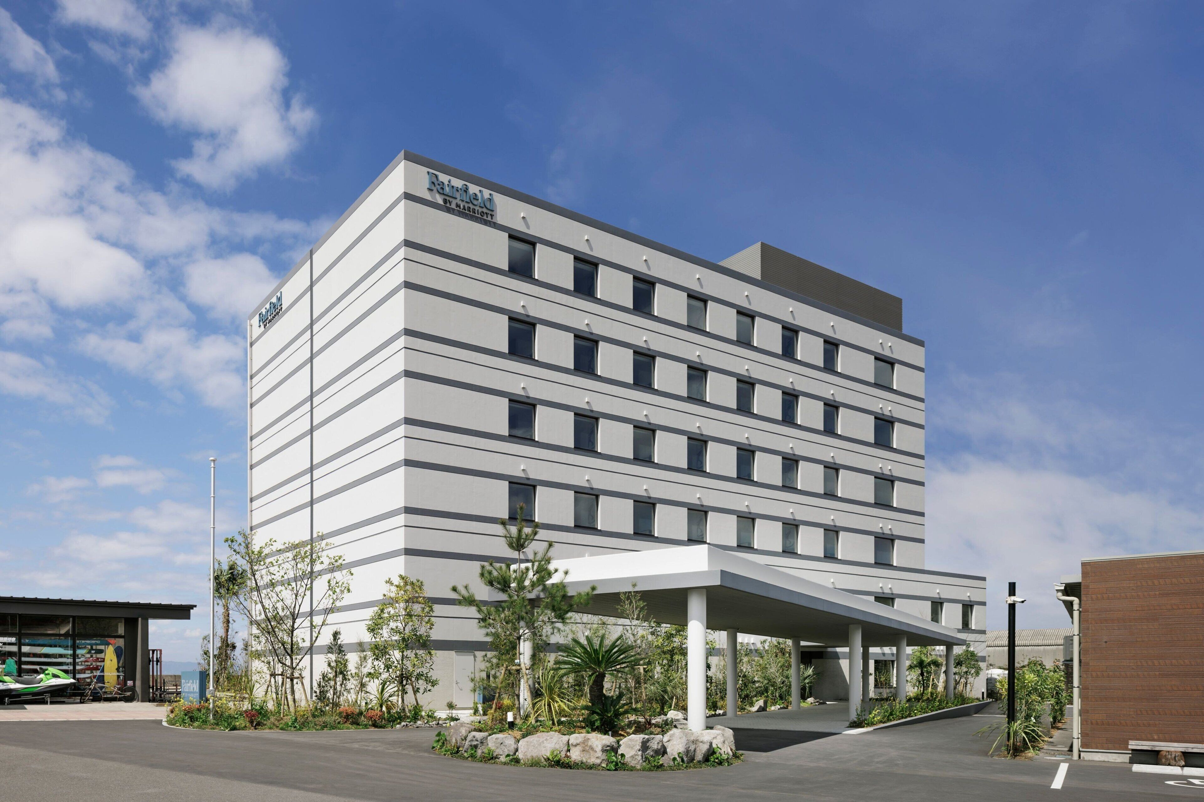 Een modern hotelgebouw met een platte gevel, meerdere ramen en een overdekte entree.