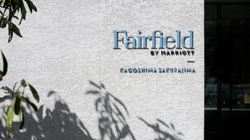 Letrero de Fairfield by Marriott con fondo de pared texturizada y sombras de hojas.