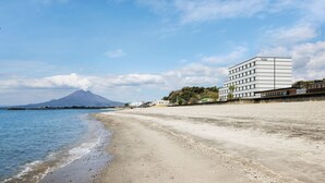 A beach with a building and a mountain in the background. - Fairfield by Marriott Kagoshima Sakurajima (Tarumizu)