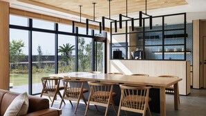 A modern kitchen with a wooden dining table and chairs, large windows, and a view of the outdoors. - Fairfield by Marriott Kagoshima Sakurajima (Tarumizu)