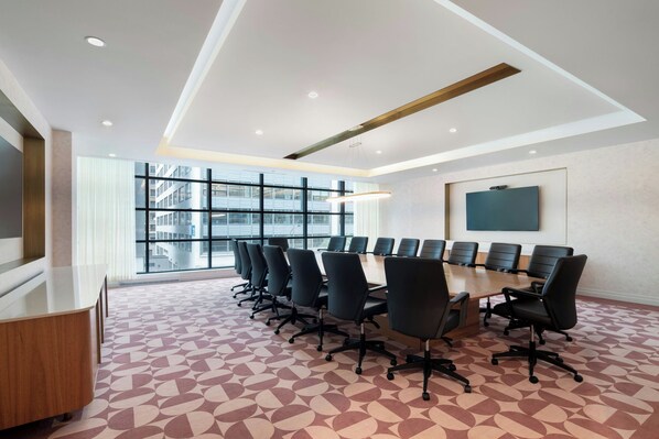 A conference room with a large table, multiple chairs, and a large window with a city view.